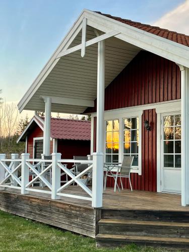 a red house with a porch and a deck at Aspudden en pärla i Sörmland in Vingåker