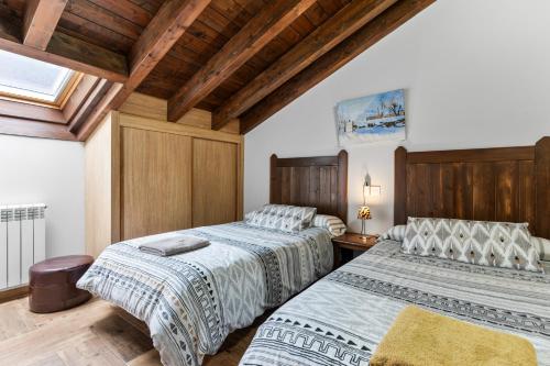 two beds in a room with wooden ceilings at La Picarota in Pajares