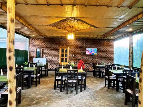 a dining room with tables and chairs and a brick wall at Volcanoes Over View Safaris & Camp in Nyarugina