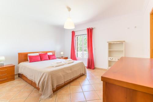 a bedroom with a large bed with red pillows at Casa Nelson e Esperanca in Vila Nova de Milfontes