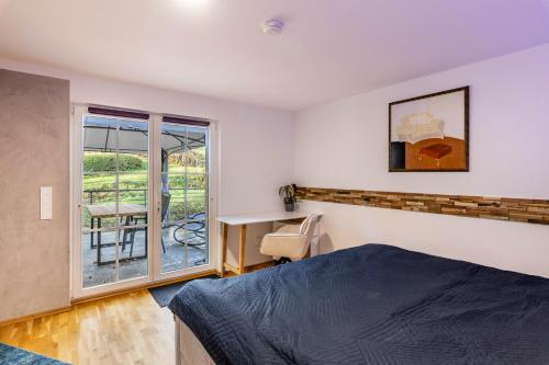 a bedroom with a bed and a desk and a window at Bergisch Resort Helle in Lindlar