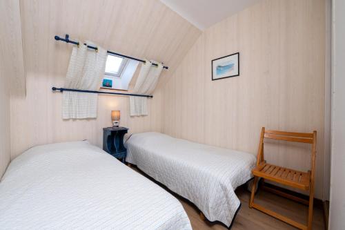 a bedroom with two beds and a chair and a window at Maison proche de la mer in Arzon