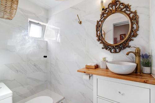 a white bathroom with a sink and a mirror at Quinta do Mestre- Casa Passarinhos in Tavira