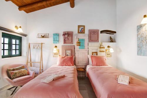 two beds in a room with pink sheets and a chair at Quinta do Mestre- Casa Passarinhos in Tavira
