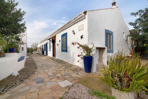 a white building with blue doors and potted plants at Quinta do Mestre- Casa Passarinhos in Tavira