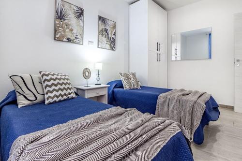a bedroom with two beds with blue sheets and a mirror at NURAS - Casa IAIA Alghero city center in Alghero