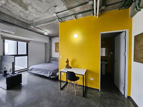 a yellow wall in a bedroom with a bed and a desk at Modern loft with panoramic views in Monterrey