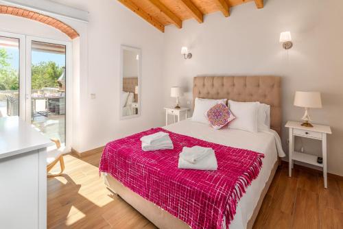 a bedroom with a large bed with a red blanket at Villa Rodrigues in Boliqueime