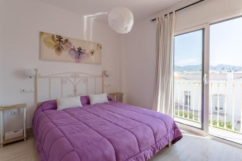 a bedroom with a purple bed and a large window at Apartamento Corazón de Nerja in Nerja