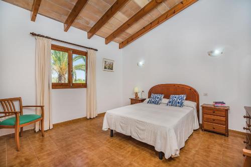 a bedroom with a bed and a chair and a window at Villa Moreno in Pollença