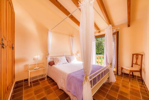 a bedroom with a canopy bed and a window at Es Fasser in Son Servera
