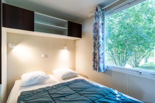 a bedroom with a bed and a window at Mobilhome du Soleil in Saint-Pompont