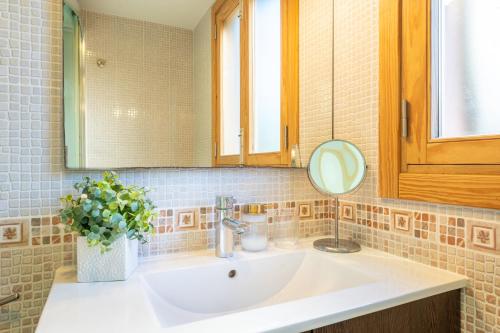 a bathroom sink with a mirror and a vase of flowers at Holytom Puerto Pollensa in Port de Pollensa
