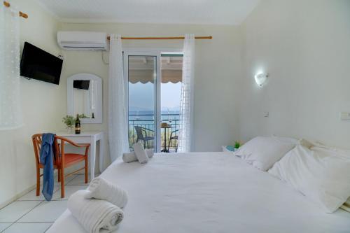 a white bedroom with a large white bed and a table at S9 room in Nikiana