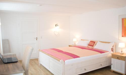 a white bedroom with a bed and a desk at kleines Landhaus Bodensee in Überlingen