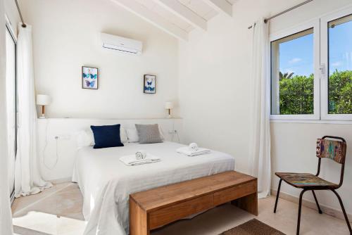 a white bedroom with a bed and a chair at Villa Mariposa in Sant Lluis
