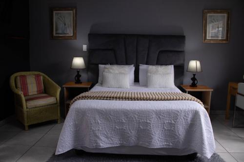 a bedroom with a large bed and a chair at Bachelor suite in Rustenburg in Rustenburg