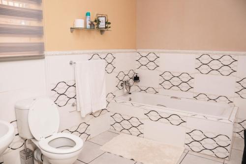 a bathroom with a toilet and a tub and a sink at Bachelor suite in Rustenburg in Rustenburg