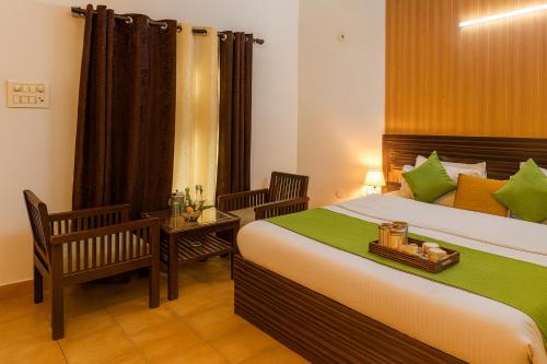 a bedroom with a large bed and two chairs at Oslo Green By Around Stays, Tapovan, Rishikesh in Rishīkesh