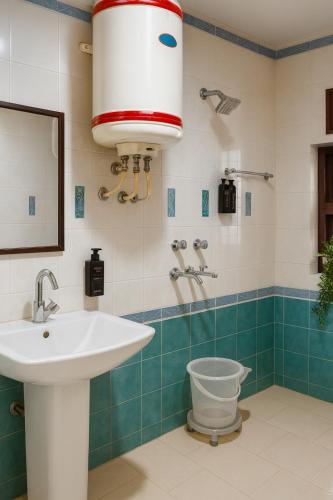 a bathroom with a sink and a toilet and a mirror at Oslo Green By Around Stays, Tapovan, Rishikesh in Rishīkesh