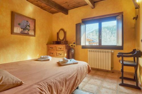 a bedroom with a bed with a window and a chair at El Mirador de Babia in Ríolago
