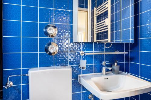 a blue tiled bathroom with a sink and a mirror at Schwarzwaldblick D App 8 mit Pool in Schönwald