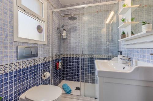 a blue tiled bathroom with a toilet and a sink at Casa Betta in Costa Calma