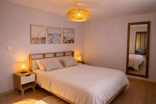 a bedroom with a large white bed and a mirror at Entre Nature et Océan in Commequiers