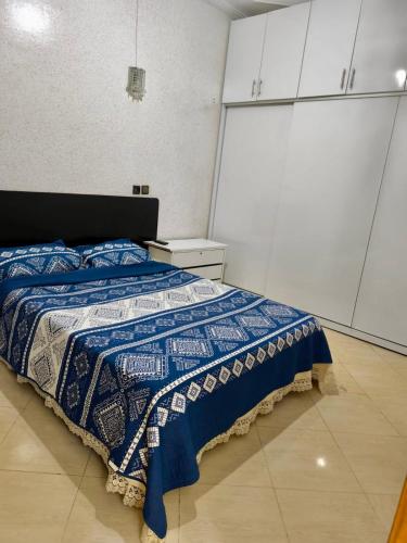 a bedroom with a bed with a blue and white blanket at Dar dyafa in Meknès