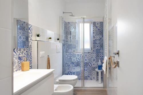 a bathroom with a toilet and a shower with blue tiles at Rosa dei Venti - Centro Storico in Varazze