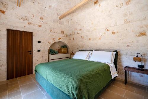a bedroom with a green bed in a stone wall at Dimora Dormio in Monopoli