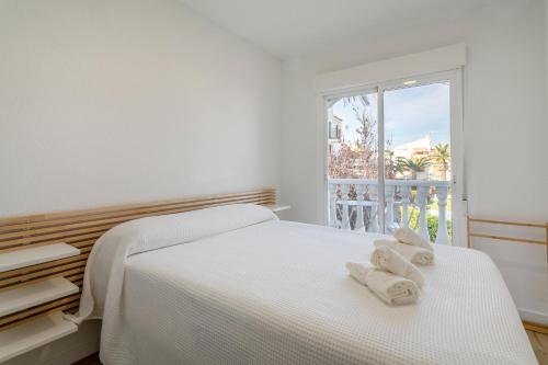 a white bedroom with a bed with towels on it at Bungalow 213 in Alicante