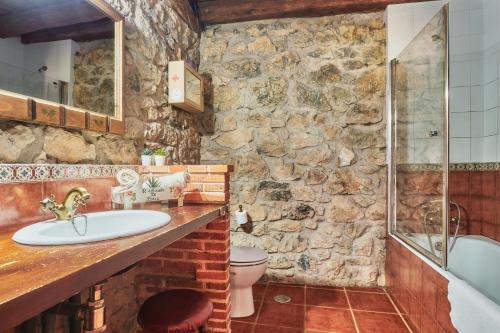 a stone walled bathroom with a sink and a toilet at El Mirador de Babia in Ríolago