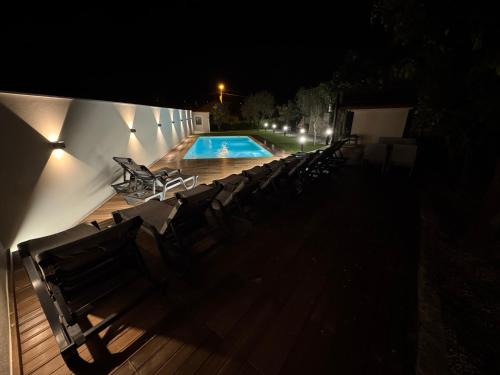 a group of chairs sitting around a swimming pool at night at Santa Baia in Veiga