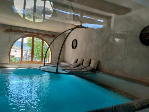 an infinity pool with chairs in a house at Gite Sublime Spa, Piscine Indoor in Mostuéjouls