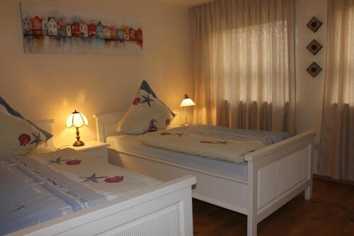a white bedroom with two beds and a window at Haus Deichbrise in Niebüll