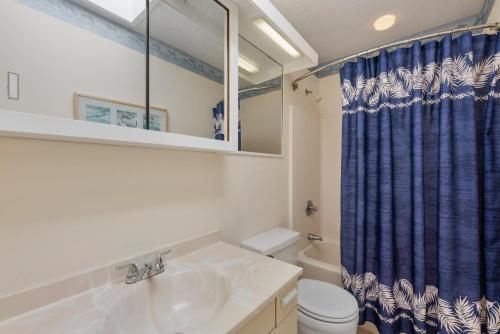 a bathroom with a sink and a blue shower curtain at Delightful Diversion in Duck