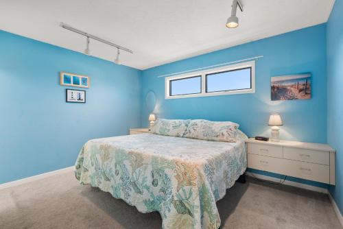 a blue bedroom with a bed and a window at Delightful Diversion in Duck