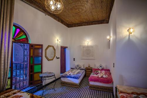 a room with two beds and a stained glass window at Dar Chbili Fès in Fez