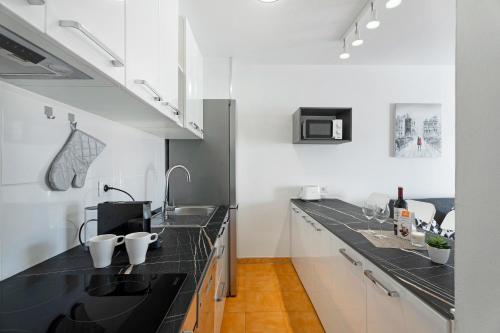 a kitchen with black counter tops and white cabinets at Ocean Park 311 in Adeje