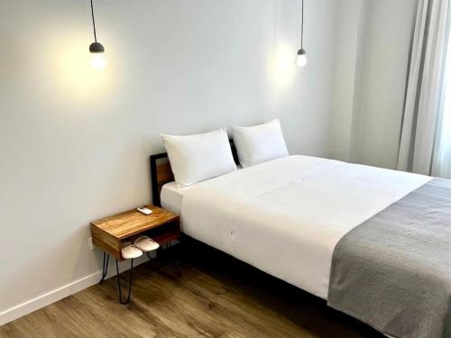 a bedroom with a large white bed and a table at Glamour Apartments in Figueira da Foz