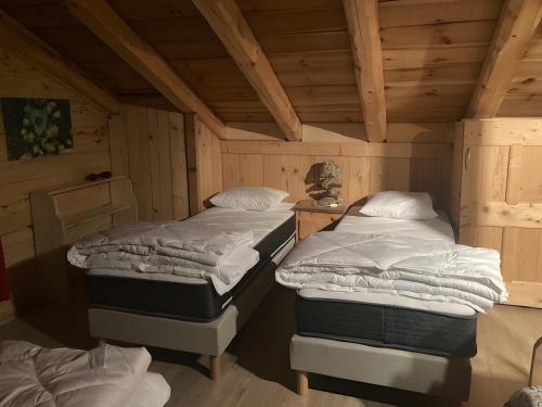 two twin beds in a room with wooden ceilings at Chalet Saint-Roch in Val Cenis