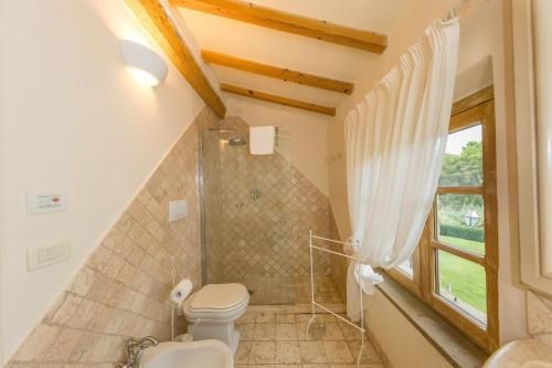 a bathroom with a toilet and a window at Villa Cava Alta in Riparbella