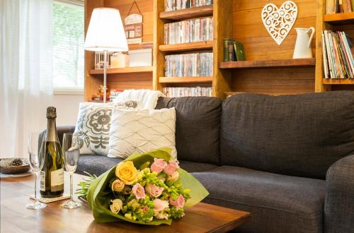 ein Wohnzimmer mit einem Sofa und einem Tisch mit einer Schüssel Blumen in der Unterkunft Cottage in the Forest in Olinda