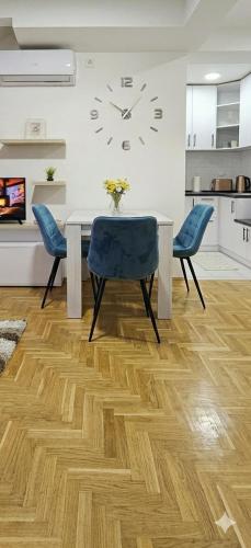 a dining room table with two chairs and a clock on the wall at Apartman Panorama 2 in Požarevac
