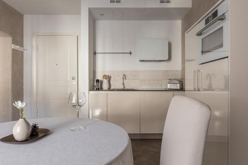 a white kitchen with a table with a glass of wine at Rennweg 114 BELAMI LIVING in Merano