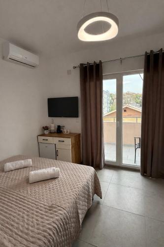 a bedroom with a bed and a tv and a window at Apolana Apartments in Negotino