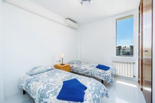 two beds in a white room with a window at La Plaza in Port de Pollensa