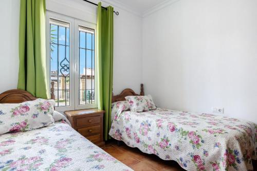 a bedroom with two beds and a window with green curtains at Casa García in Cádiz