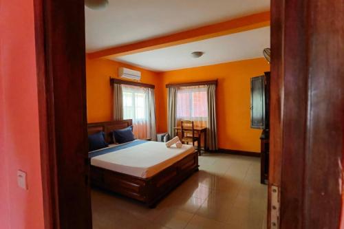 a bedroom with orange walls and a bed and a television at Hôtel Concorde in Antsiranana